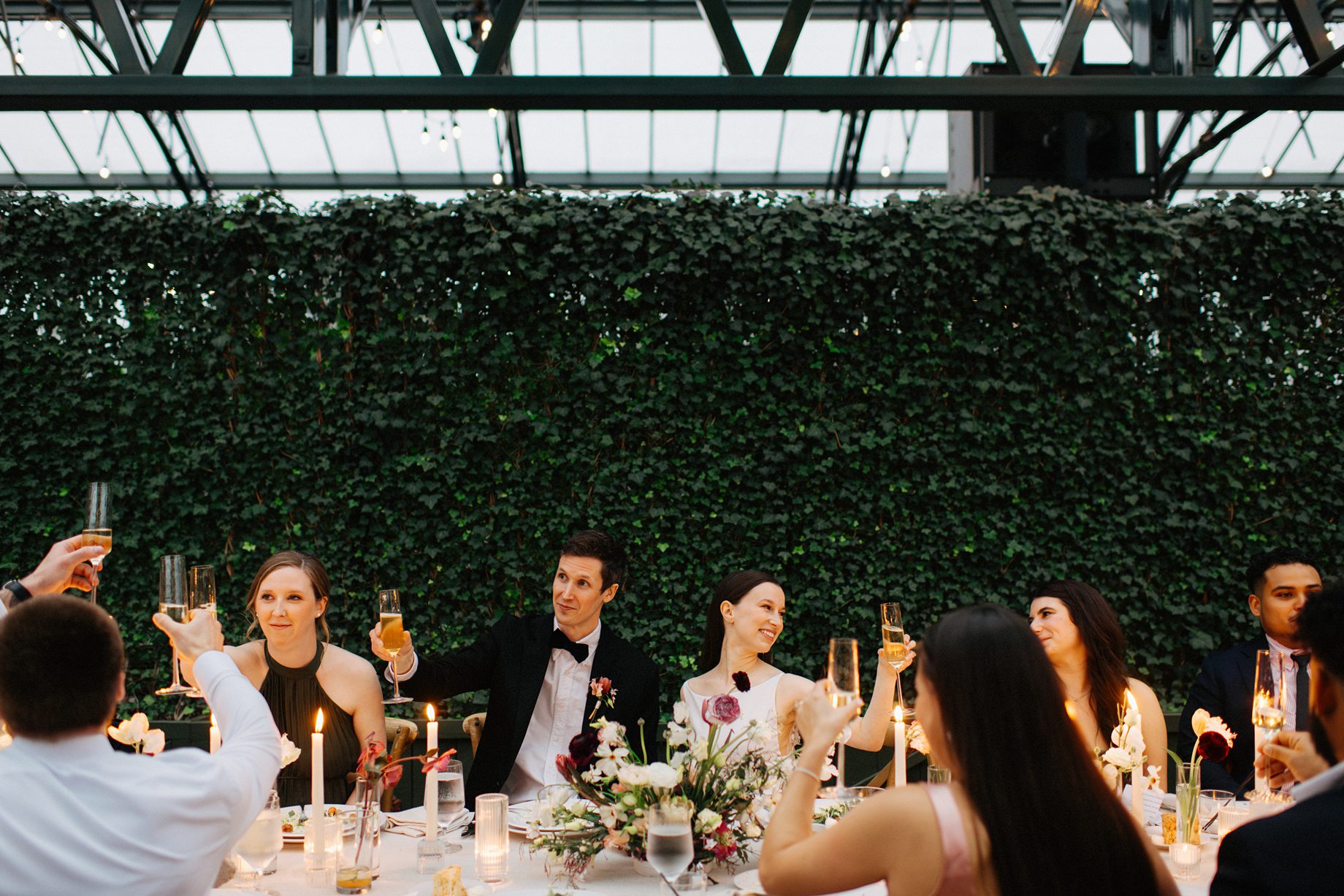 043a Bride and groom raising their glasses at their wedding at Planterra Conservatory photographed by wedding photographer Heather Jowett