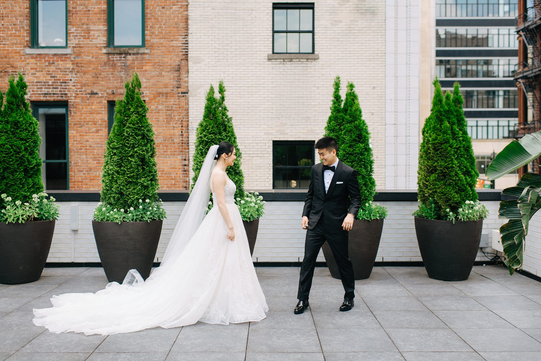 Candid moment from the couples first look on the rooftop terrace of the Shinola Hotel in Detroit captured with a timeless documentary feel against the citys signature backdrop