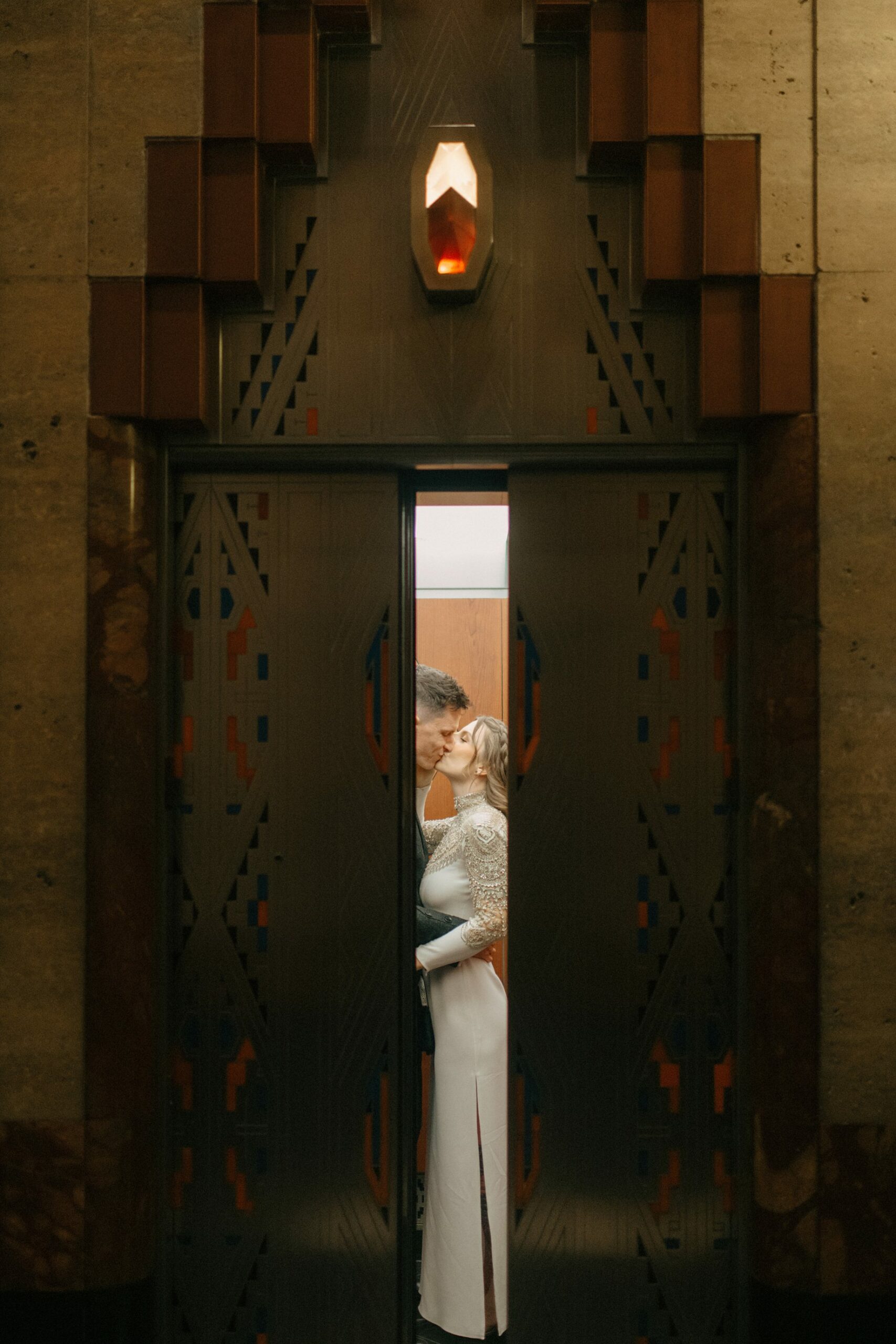 Bride and groom kiss in a vintage art deco elevator at the Guardian Building in a cinematic Detroit wedding photograph