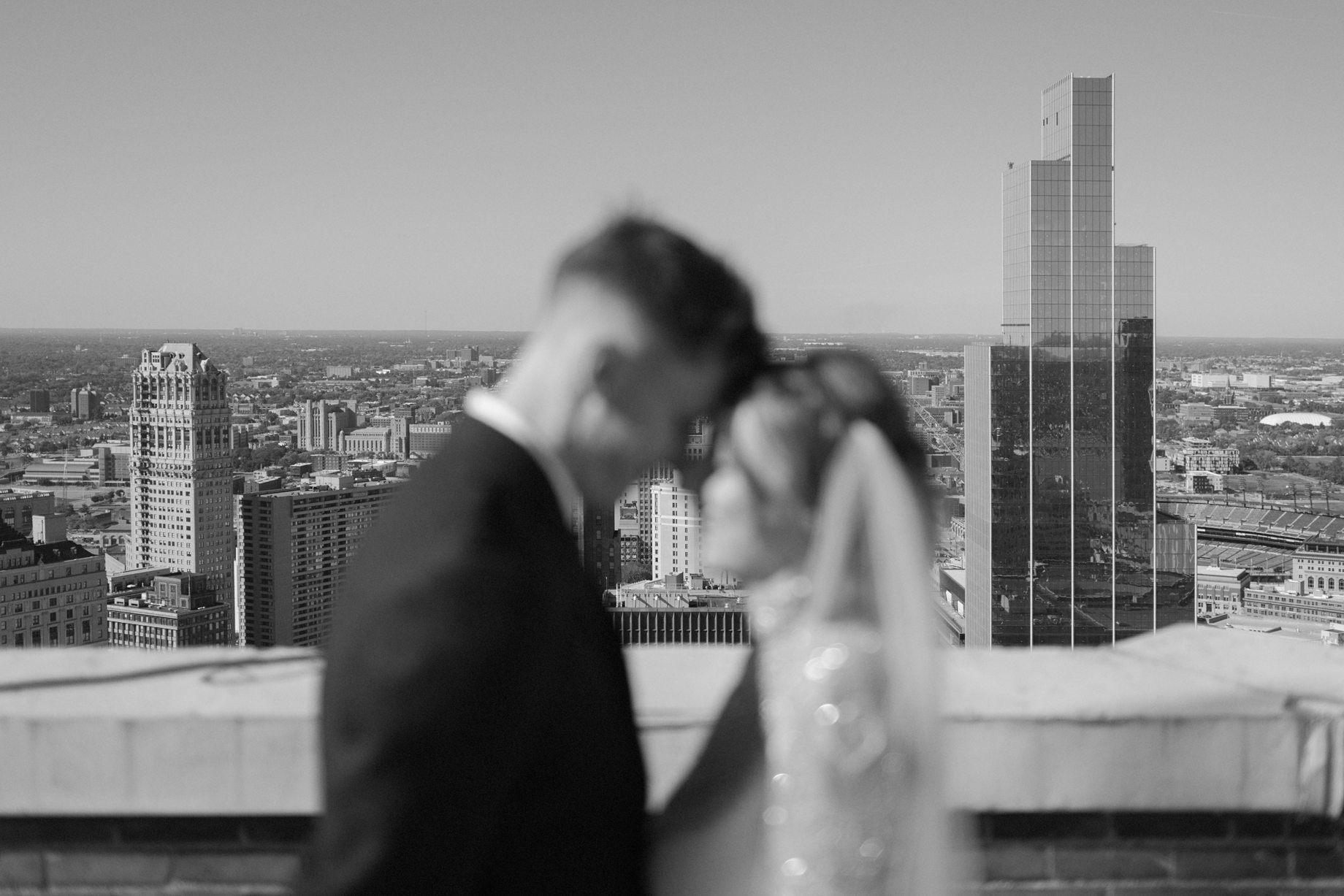 Detroit skyline stretches into the distance as bride and groom share a quiet moment in soft focus