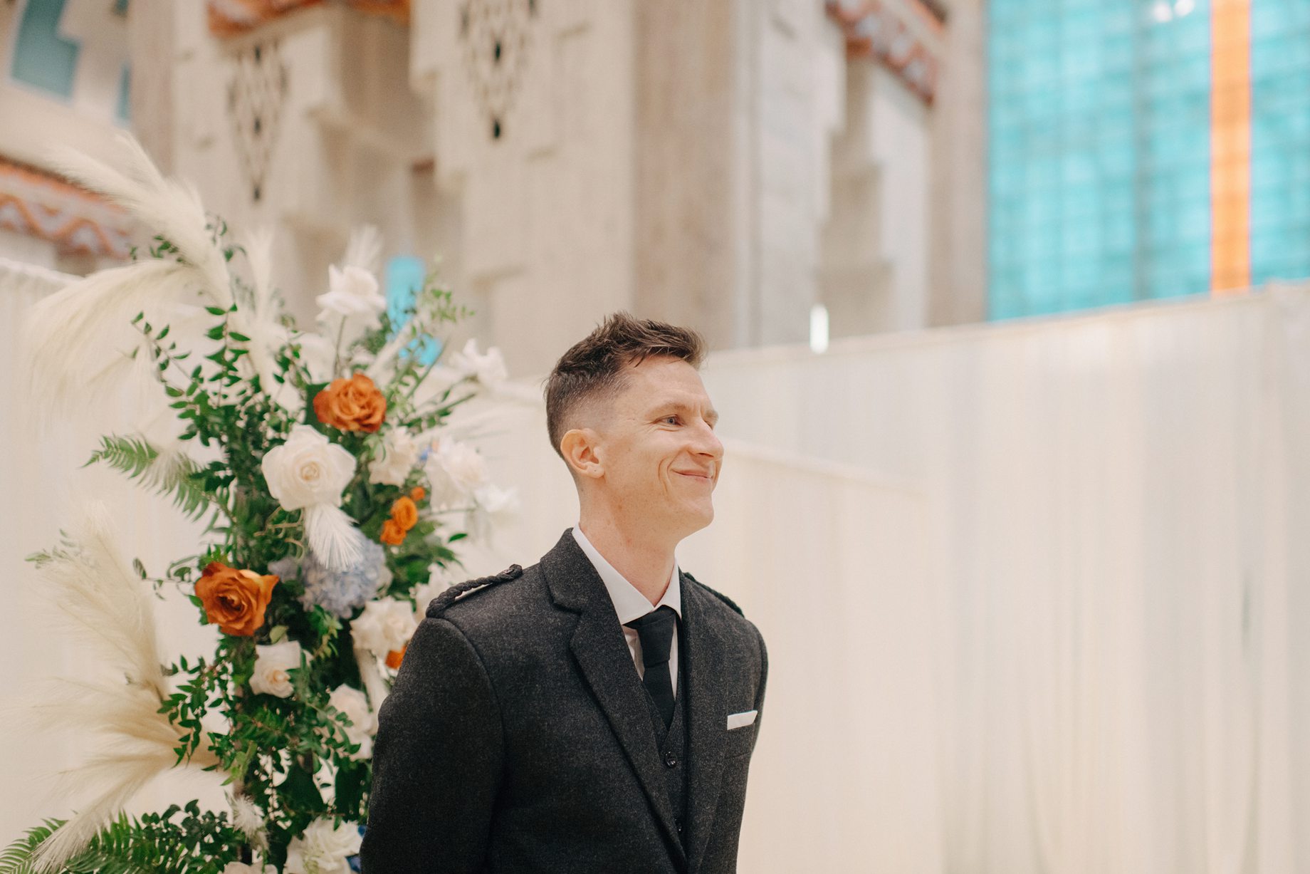 Groom watches on as bride walks down the aisle during a wedding at the guardian building in downtown Detroit