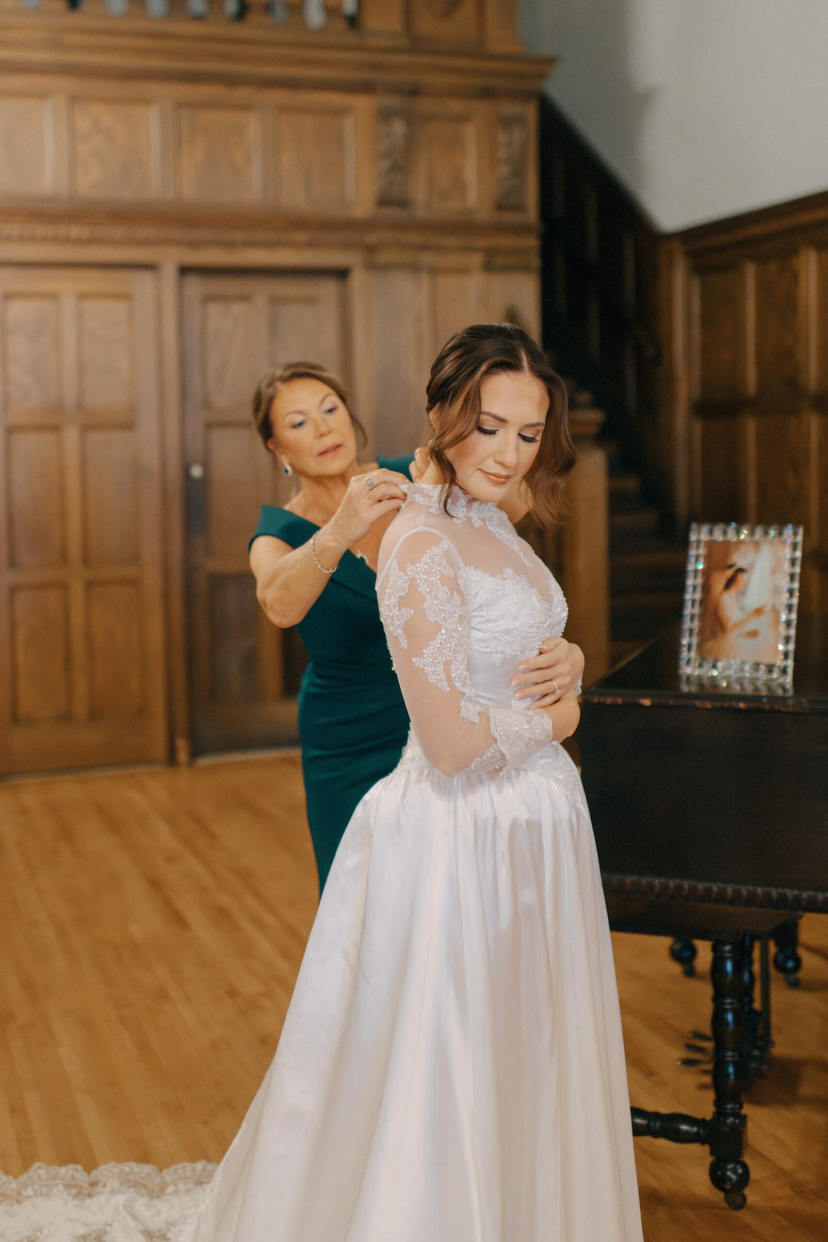 Mother helping bride into the wedding dress she wore on her own wedding day at a Detroit Masonic Temple wedding by Fine art Detroit wedding photographer Heather Jowett