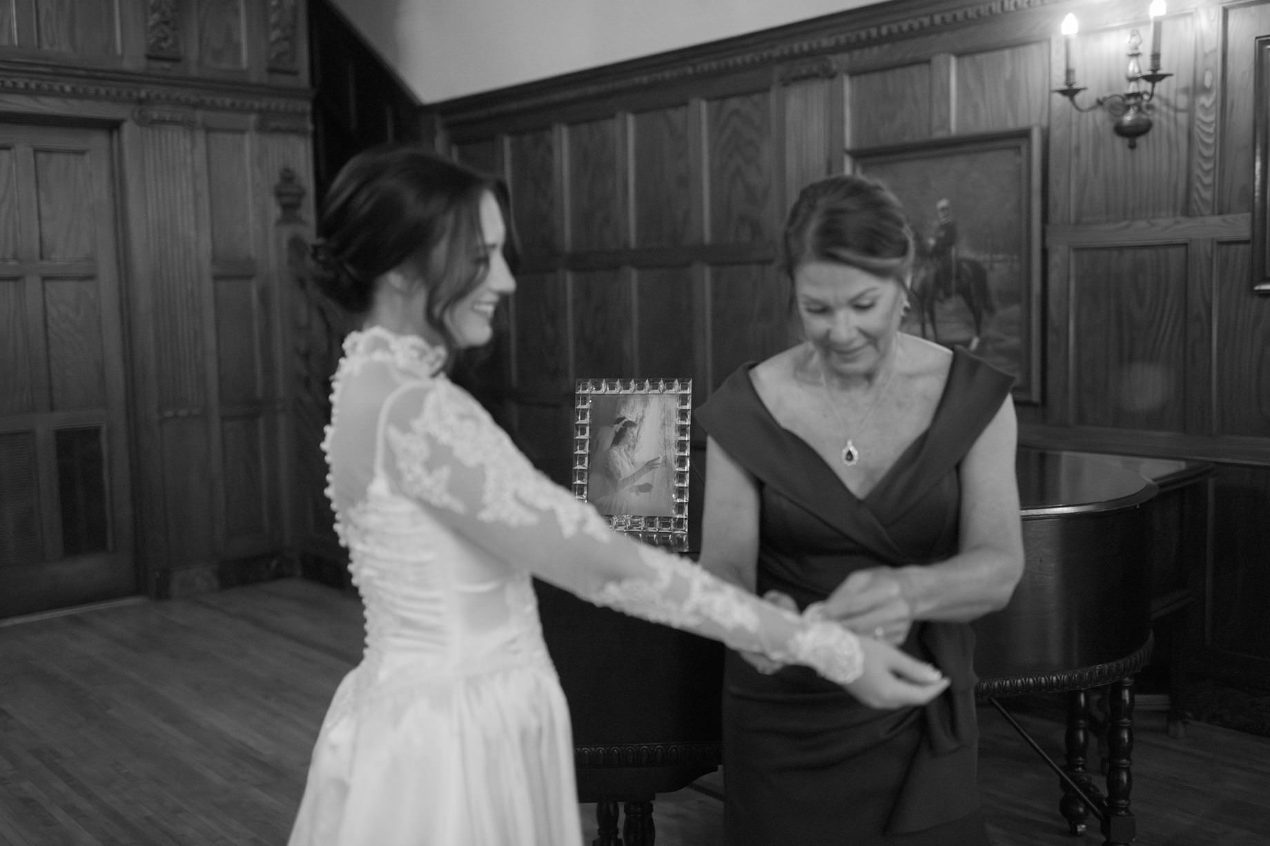 Mother helping bride into the wedding dress she wore on her own wedding day by Fine art Detroit wedding photographer Heather Jowett