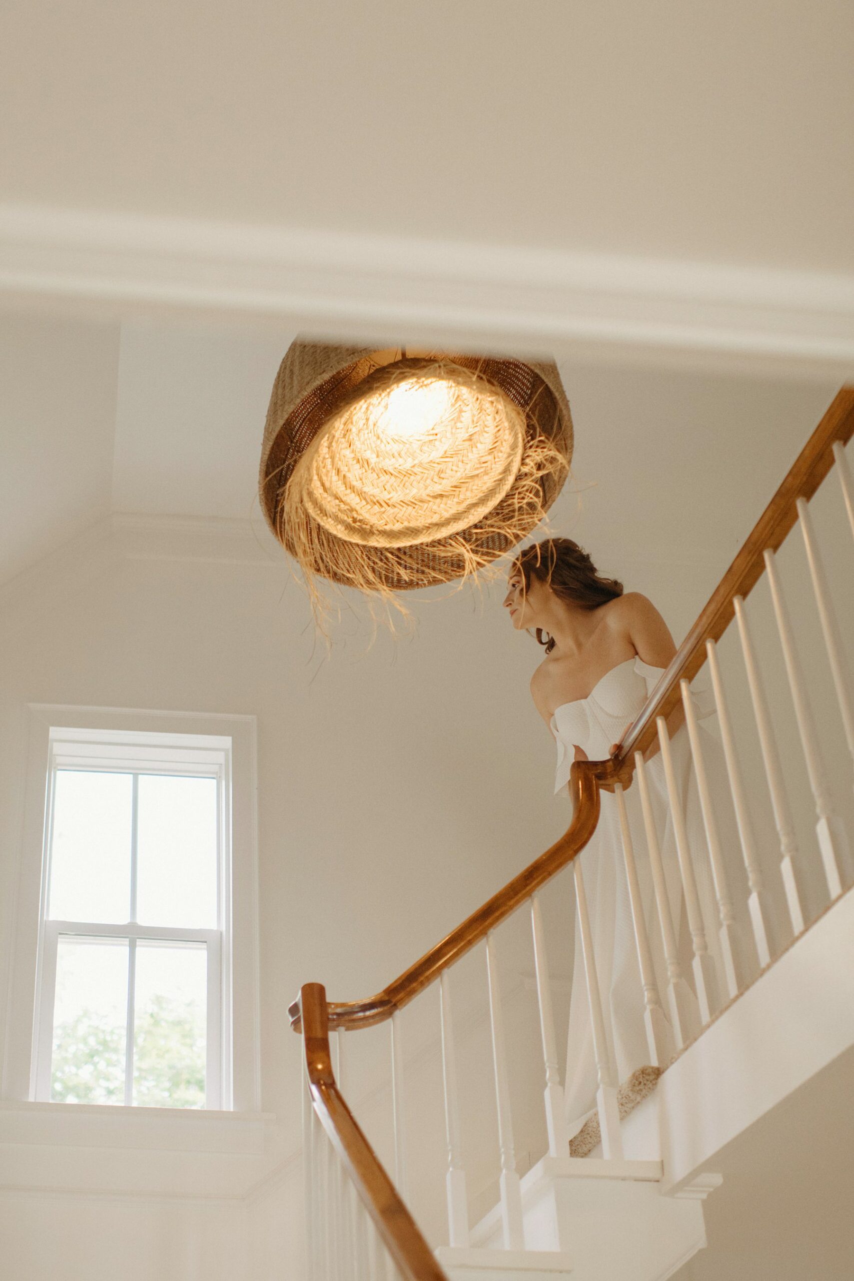 Bride peeks down staircase in natural light at Glass House Community