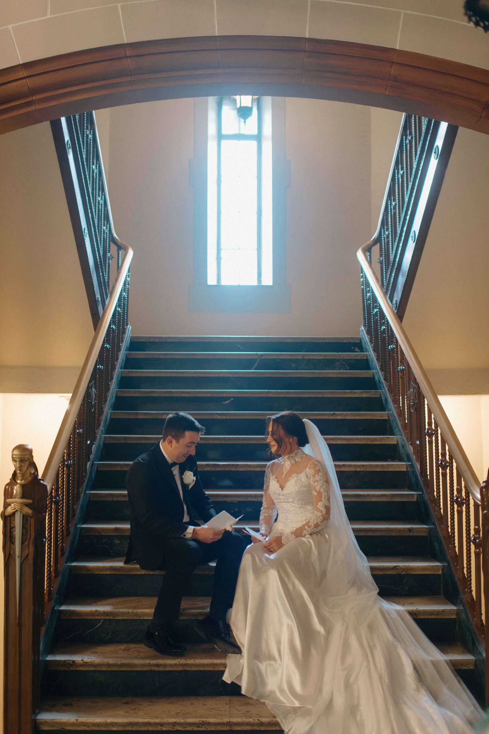 Bride and groom share private vows on the grand staircase of the Detroit Masonic Temple an emotional fine art moment in this luxury Masonic Temple wedding