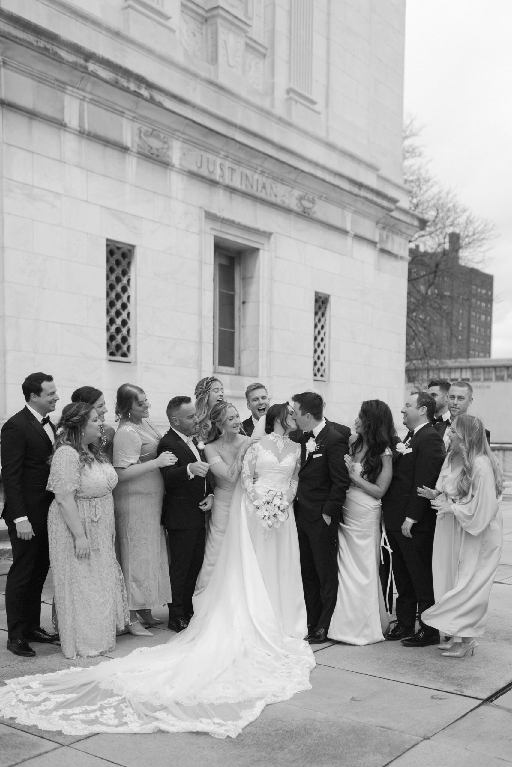 Bride and groom surrounded by their wedding party outside of the Detroit Public Library