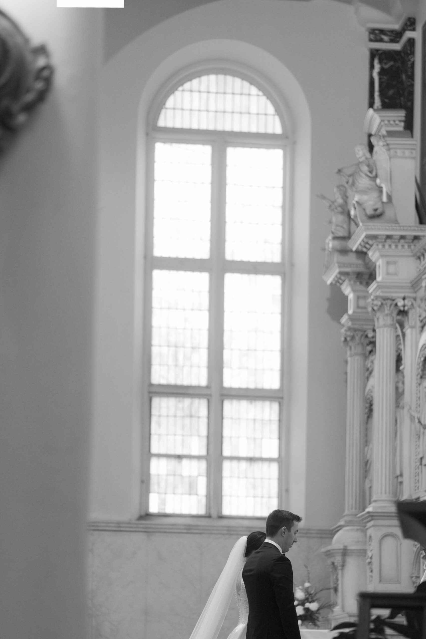 Artful black and white image of the bride and groom at the altar of Saints Peter and Paul Jesuit Church in Detroit