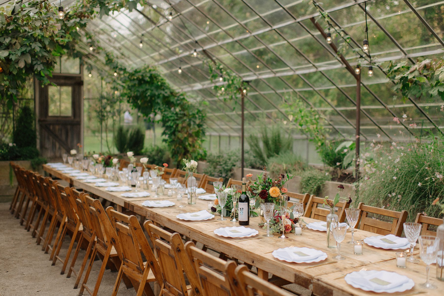 Fall wedding reception table set with vintage crystal glassware white scalloped plates and amber floral centerpieces