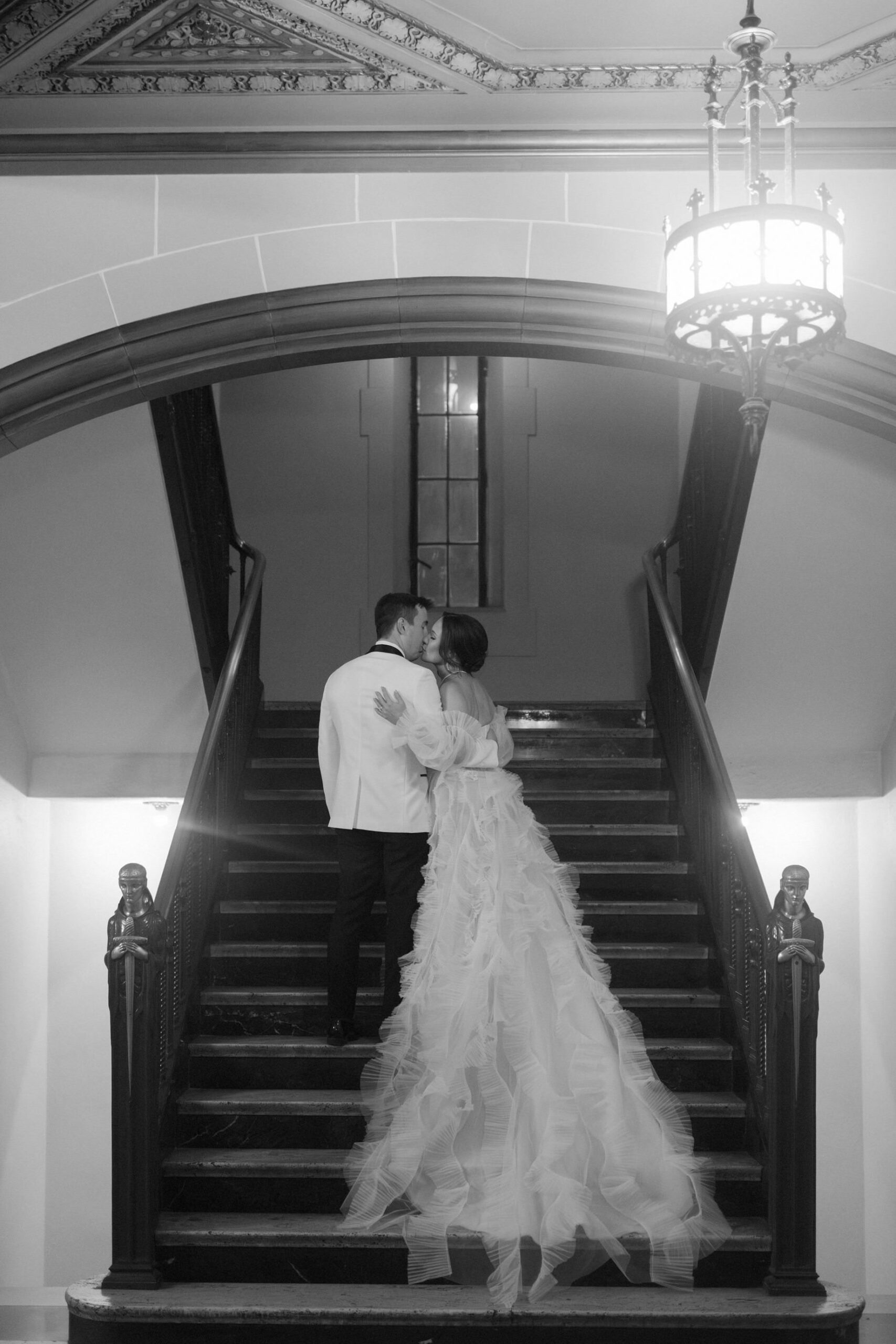 Black and white wedding photo of couple kissing on the grand staircase