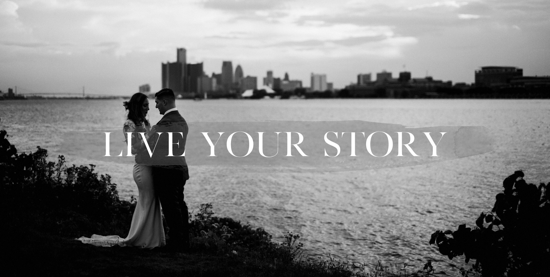 a couple poses with the detroit skyline in the background on belle isle by wedding photographer heather jowett