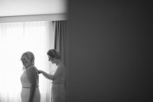 The maid of honor helps the bride into her wedding dress before her Gem Theater wedding in Detroit,