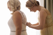 The maid of honor helps the bride into her wedding dress before her Gem Theater wedding in Detroit,