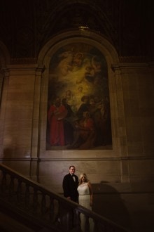 A bride and groom pose for portraits inside the Detroit public library.