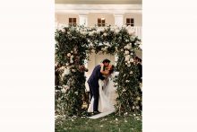 bride and groom kiss in front of cornman farms farmhouse