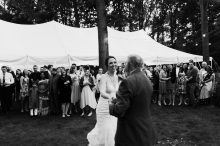 bride dancing with her father as wedding guests look on