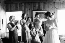 bridesmaids react enthusiastically to a bride getting into her dress
