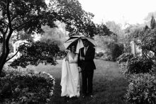 a couple posing for portraits on a rainy wedding day