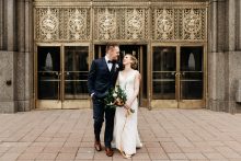 bride and groom pose for a portrait outside of the fisher building