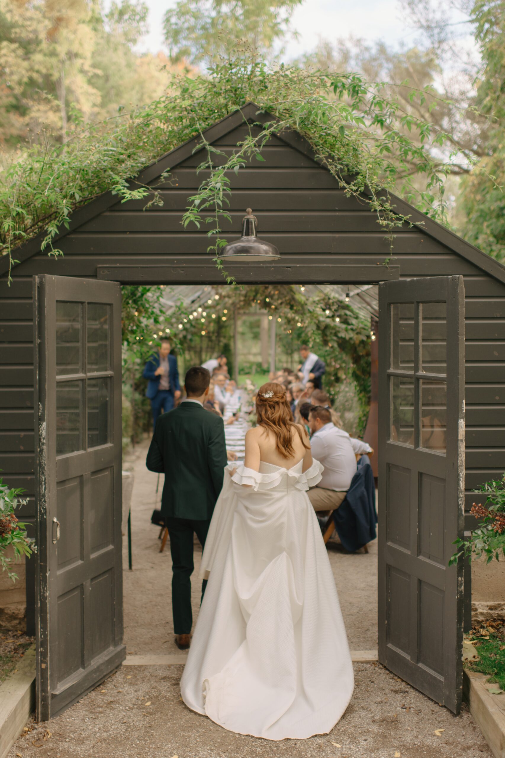 Bride and groom walking into greenhouse.