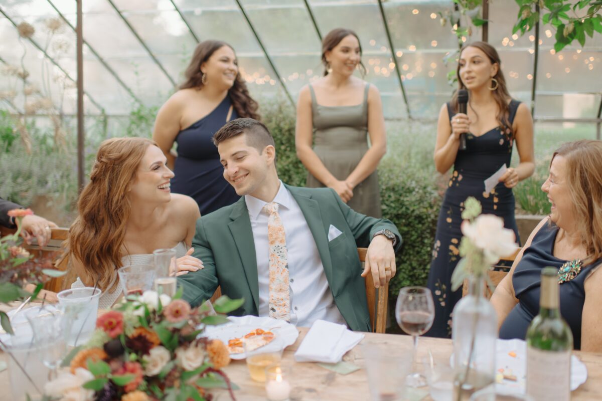 Bride and groom laughing during toasts.