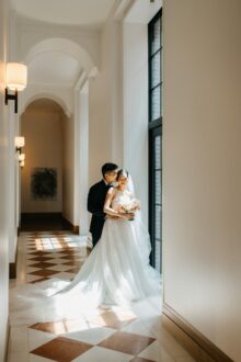 Romantic portrait of the couple bathed in soft light near the arched hallway windows at the Shinola Hotel in Detroit captured in Heather Jowetts timeless fine art style