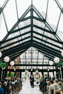 The couple stands beneath a glass conservatory ceilingin the birdy room at the shinola hotel