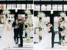 Bride and groom exhchanging rings and a first kiss in front of a lush floral backdrop