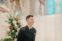 Groom watches on as bride walks down the aisle during a wedding at the guardian building in downtown Detroit