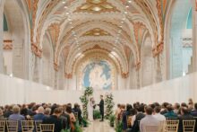 Bride and groom exchange vows inside the Guardian Building beneath its iconic ceiling in a luxury Detroit wedding ceremony at the historic art deco venue