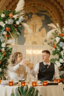 Bride and groom clink glasses after speeches during their wedding reception in the lobby of the Iconic Guardian Building