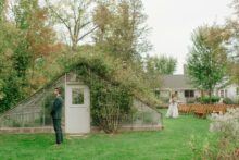 06a Bride walks across lawn toward groom for their first look by the greenhouse