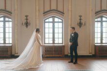 Fine art first look between bride and groom inside the Detroit Masonic Temple framed by soaring gothic windows by Detroit Wedding Photographer Heather Jowett
