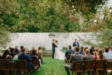 couple exchanges their first kiss as bride and groom in front of the greenhouse