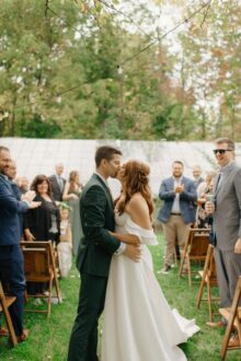 couple pausing for one more kiss as they walk back down the aisle after their glass house community wedding