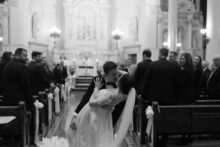Black and white photo of bride and groom kissing dramatically during the recessional walk down the aisle at Saints Peter and Paul Jesuit Church by detroit wedding photographer heather jowett