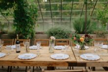 Wine bottle and bud vase detail at greenhouse wedding reception with fine art documentary photography styling