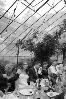 bride and groom laughing together as a toast draws smiles from guests at their greenhouse wedding at Glass House Community