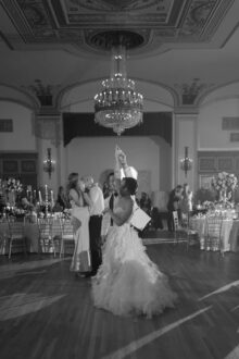 photo of bride and groom dancing beneath the chandelier at a wedding in the Detroit Masonic Temple Crystal Ballroom captured in fine art documentary style by a Detroit wedding photographer