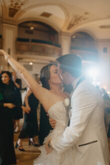Romantic moment as bride kisses groom with her arm raised triumphantly during the dance party at their Detroit Masonic Temple wedding