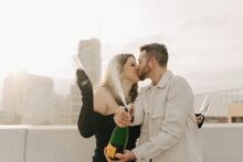 Couple popping champagne during a rooftop engagement session