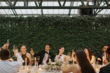 Bride and groom raising a glass with their guest