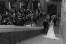 Bride and groom walking down a staircase to their cocktail hour in the Kresge court.
