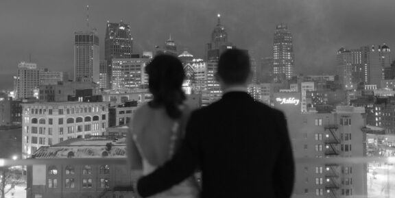 A couple overlooking the Detroit skyline on their wedding day from the DAC rooftop.