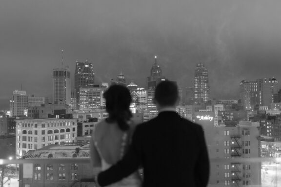 A bride and groom overlooking the Detroit skyline from the roof of the DAC.