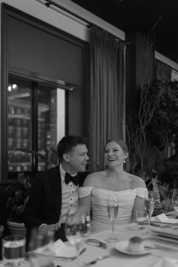 A bride and groom laughing during speeches at their Book Tower Wedding.