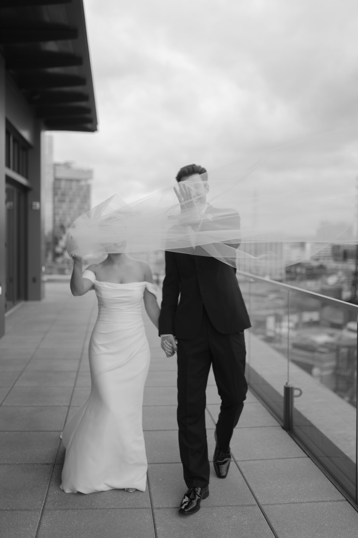 A bride's veil blowing in the wind on the rooftop of the Detroit Athletic Club during their wedding reception.