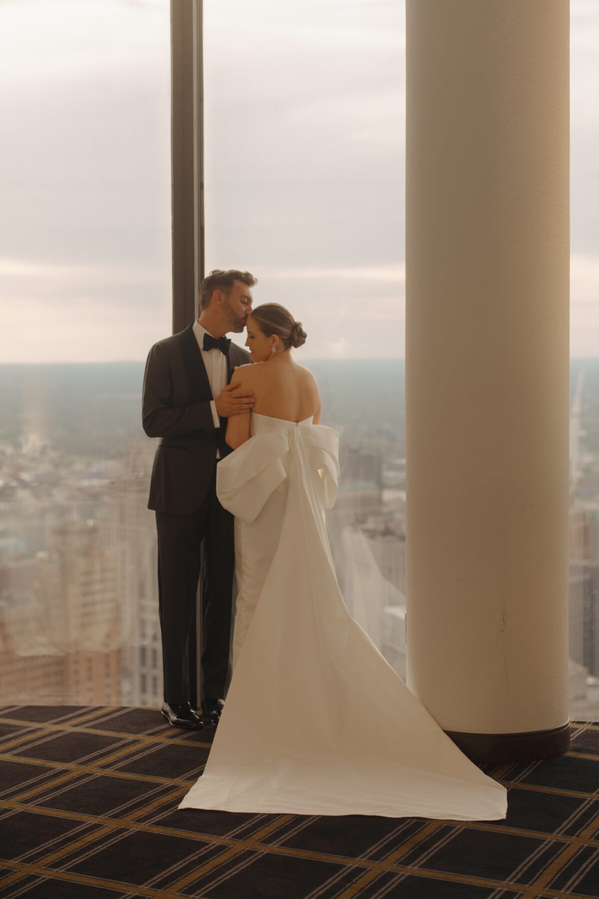 A portrait of a couple on their wedding day at Highlands in Detroit with a view of the Detroit Skyline behind them.