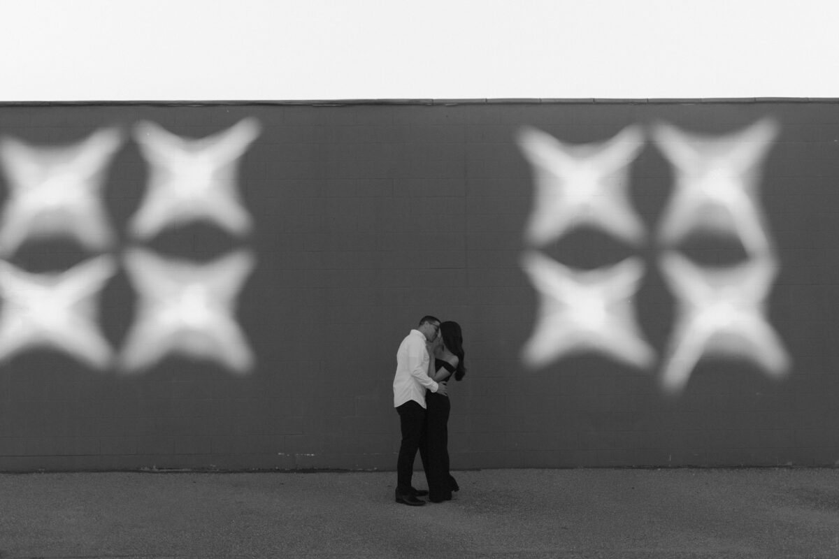 Couple embracing in front of a wall with dramatic light.